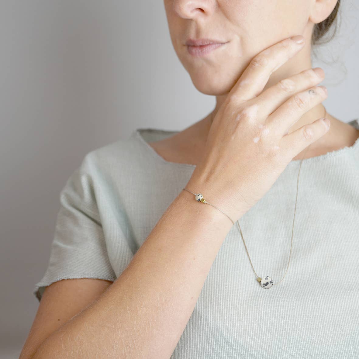 Teilansicht einer Frau, die auf einem hellen T-Shirt die Kette Alma trägt sowie das passende Armband