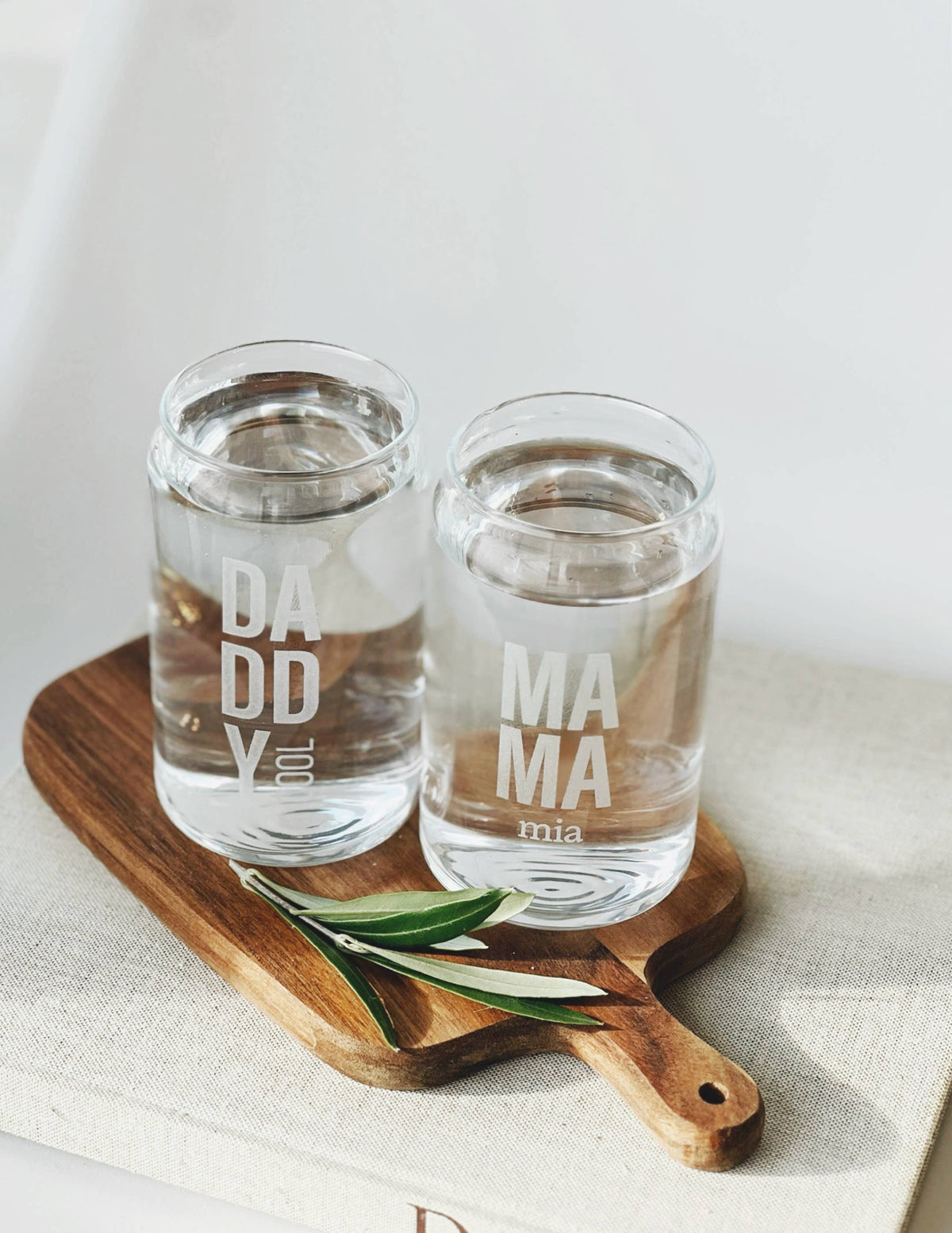 zwei Trinkgläser auf einem Holztablett mit dem Aufdruck "daddy cool" und "Mama Mia"