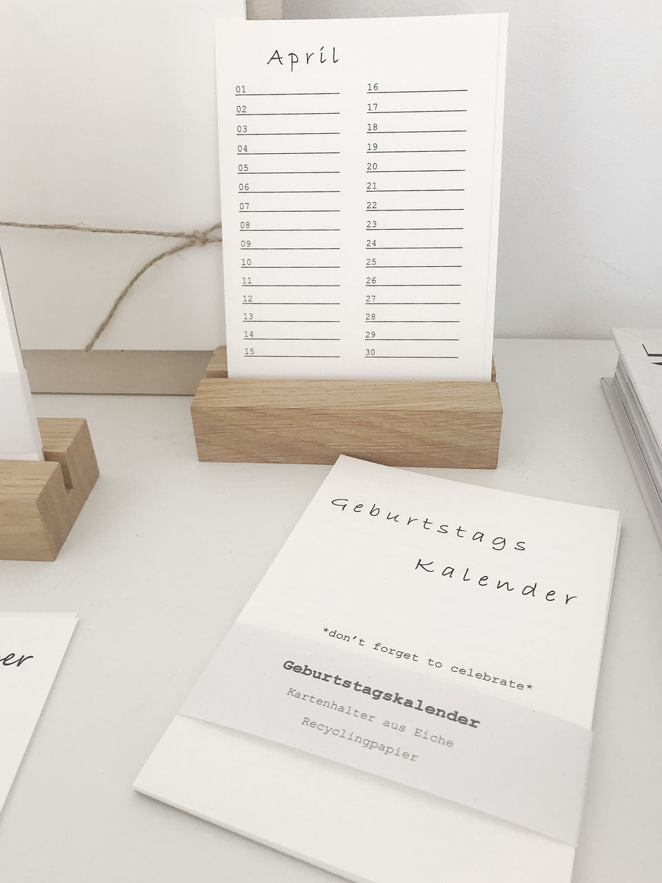 Minimalistischer Geburtstagskalender aus Recyclingpapier mit einem Halter aus Eiche. Davor liegen die Kalenderblätter.