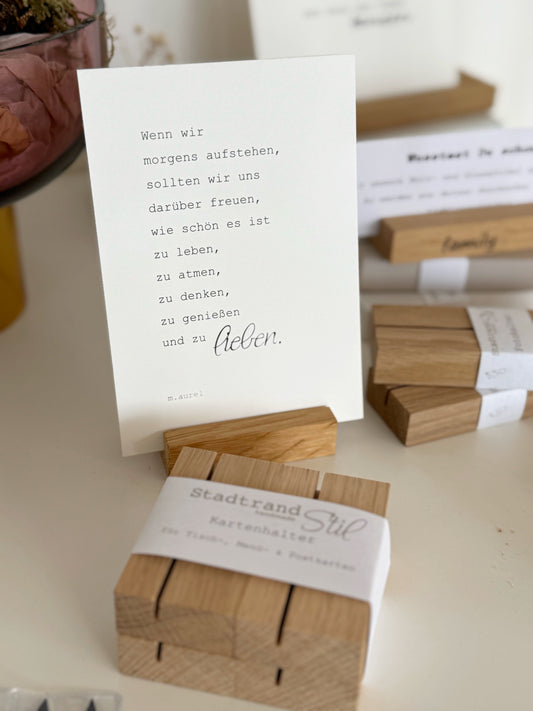 4er Set mit Kartenhaltern aus Eiche, dahinter Postkarte mit Text in einem der Halter