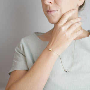 Teilansicht einer Frau, die auf einem hellen T-Shirt die Kette Alma trägt sowie das passende Armband