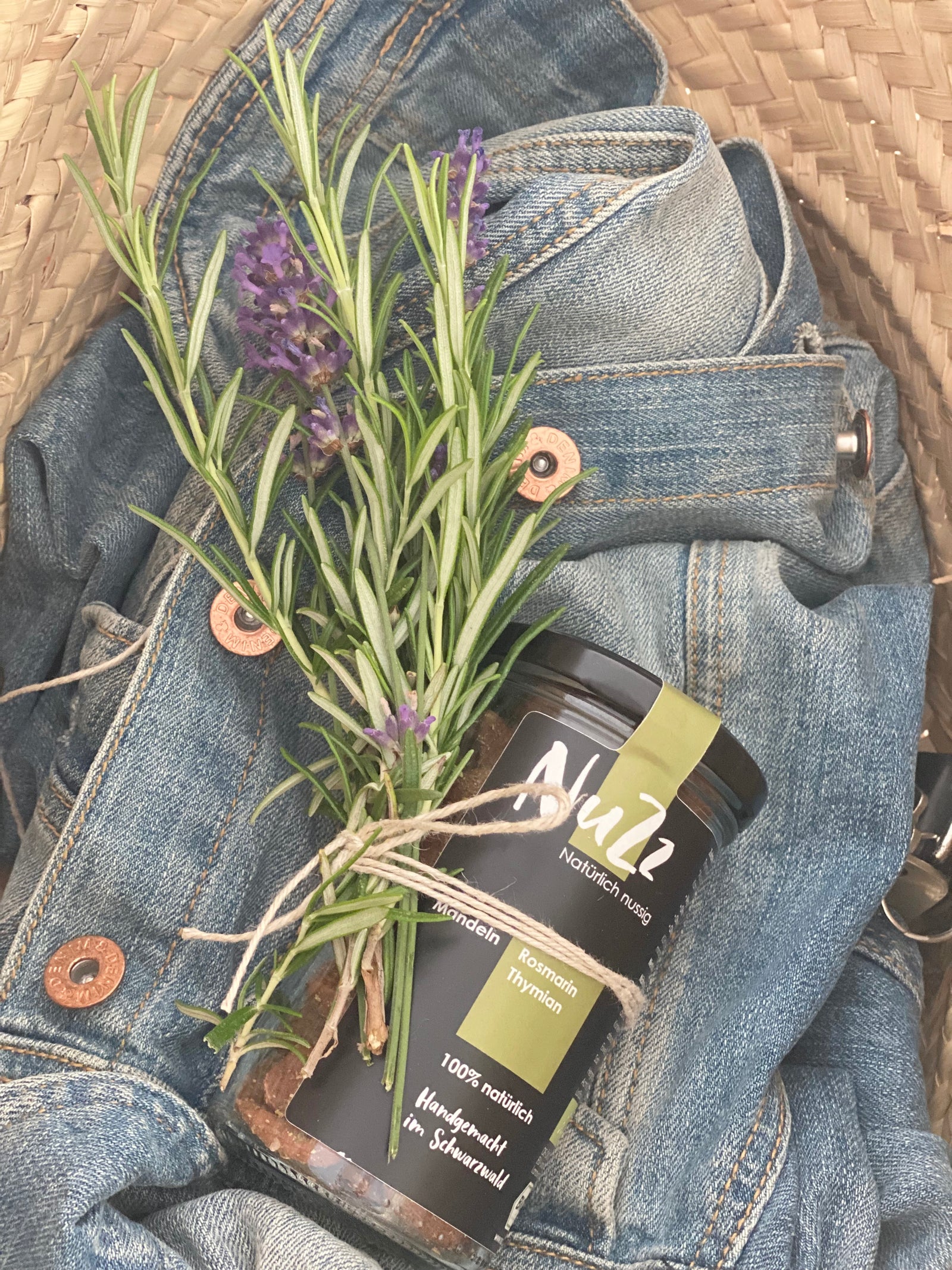Glas mit Rosmarin Nüssen als Geschenk mit Rosmarin und Lavendelzweig von Stadtrandstil, Conceptstore. Liegt auf einer Jeansjacke