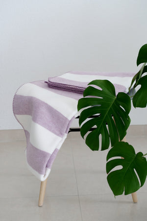 Blockstreifen Decke auf Bank, im Vordergrund Monstera Blatt