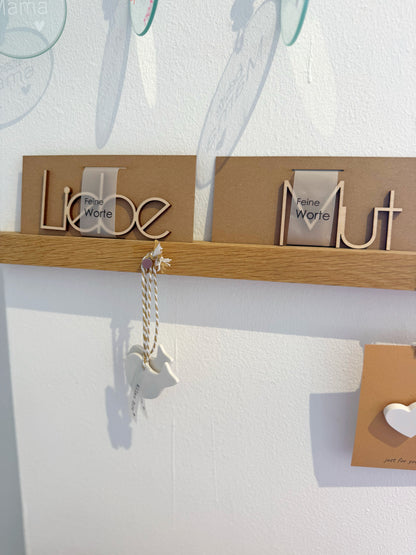 Schriftzug "Liebe" und "Mut" aus Holz auf Holzleiste