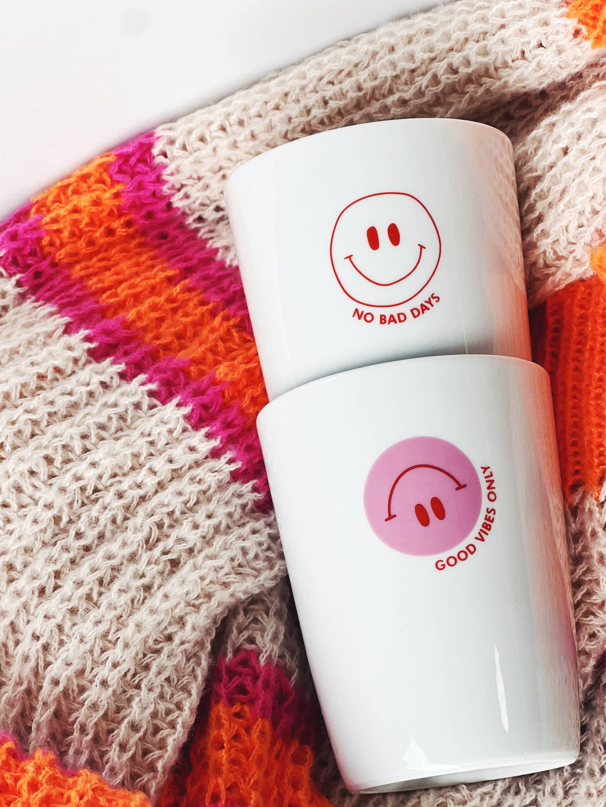 Zwei weiße Becher mit einem roten Smiley und dem Aufdruck "no bad days" und rosa Smiley und "good vifes only"