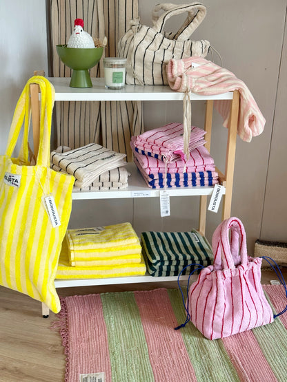Handtücher und Taschen mit fröhlichen Streifen in einem Regal