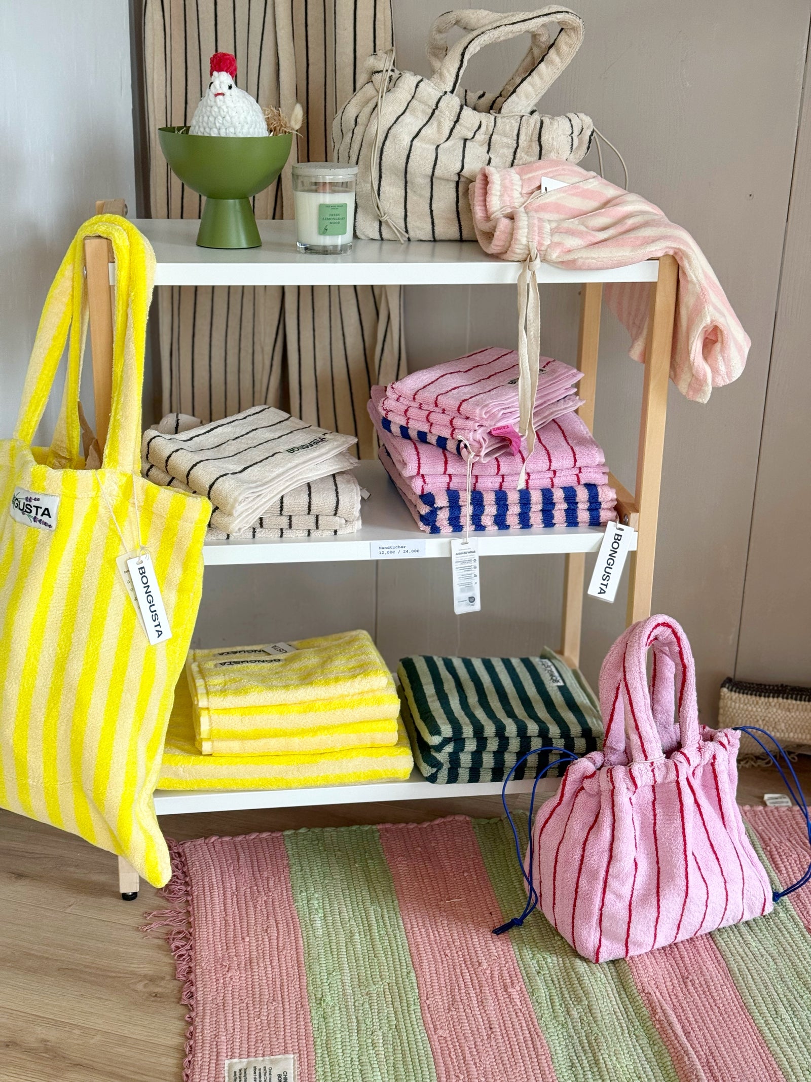 Handtücher und Taschen mit fröhlichen Streifen in einem Regal
