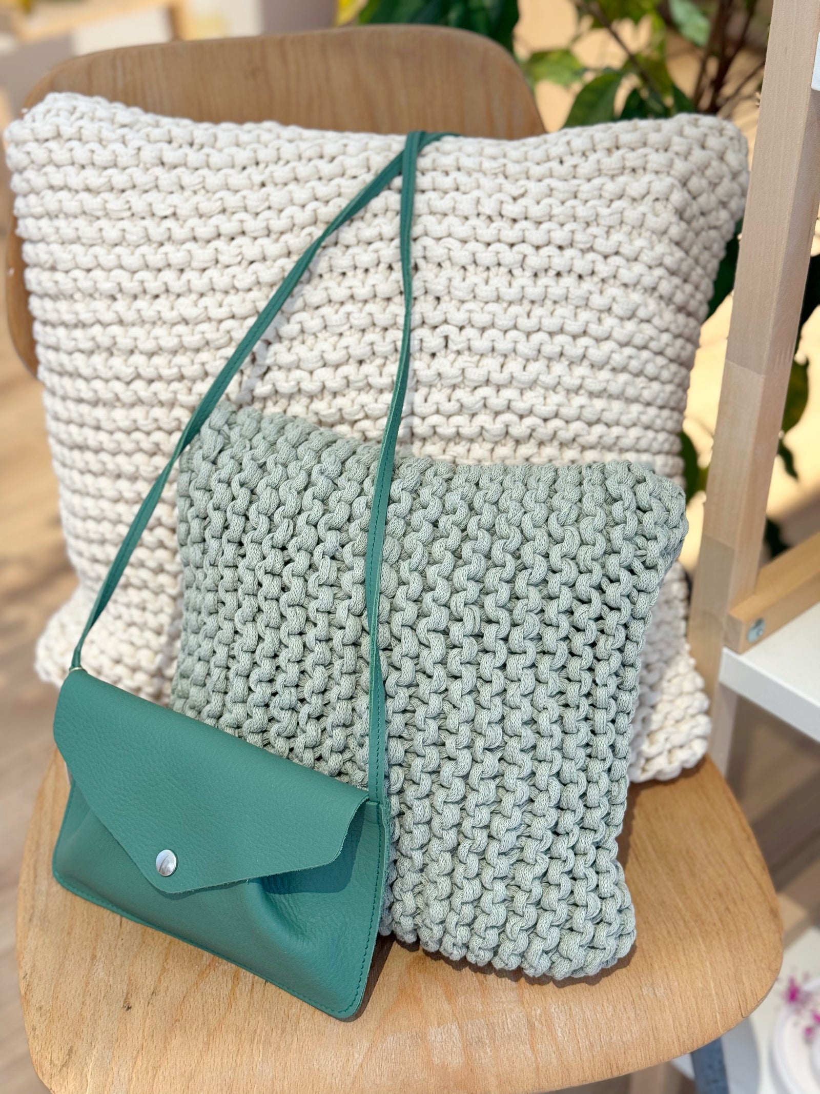 Mehrere kleine, handgearbeitete Kissen aus Recyclingmix in verschiedenen Naturtönen auf Rattansessel