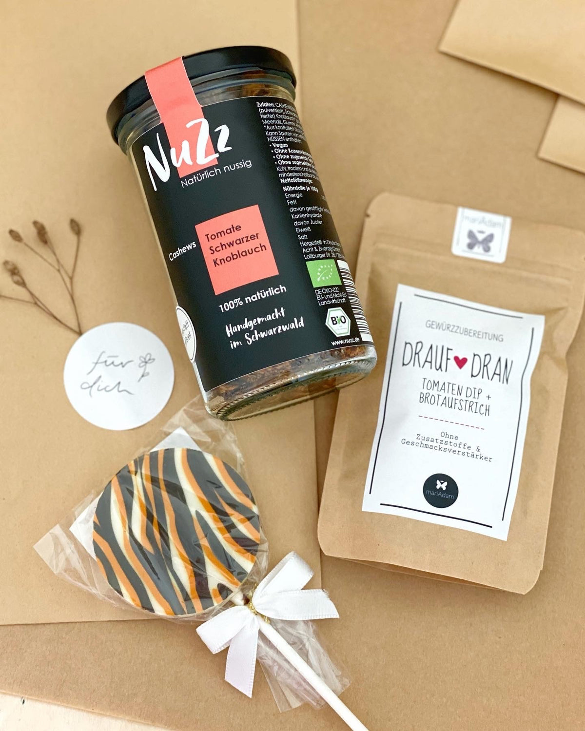 Geschenktüten aus Kraftpapier, natürlich dekoriert, darauf ein Glas Gewürznüsse, eine Tüte mit Gewürzmischung und ein Schokoladen Lolli im Zebramuster. Conceptstore Stadtrandstil