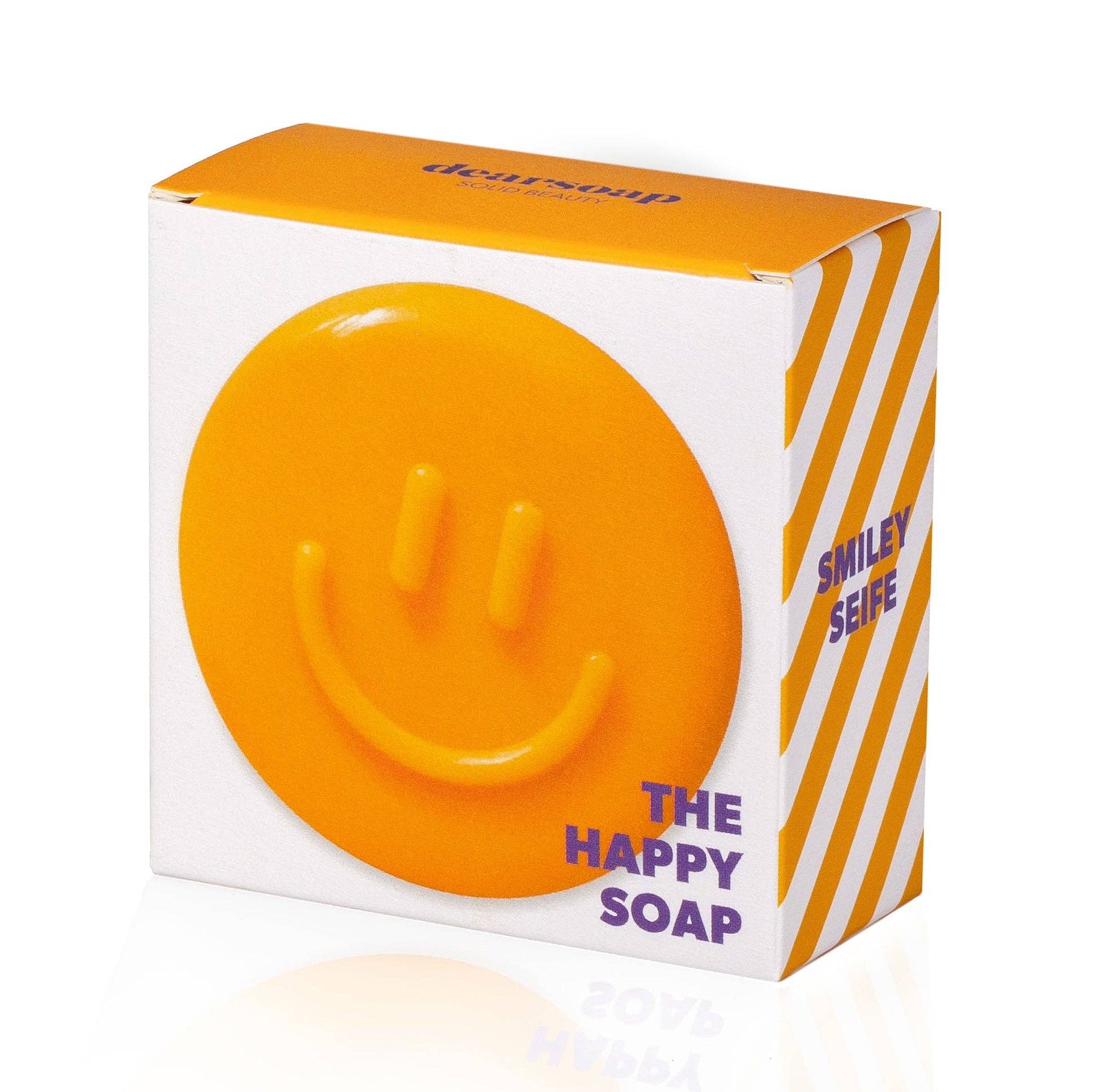 gelbe, runde seife mit Smiley auf dazugehöriger Verpackung, im Hintergrund die Seife in orange