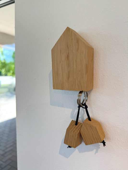 Schlüsselbord in Hausform mit zwei angehängten Schlüsselanhängern
