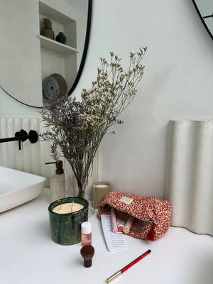 Gefllter, offen liegender kulturbeutel in einem weißen Bad , trockenblumen als deko