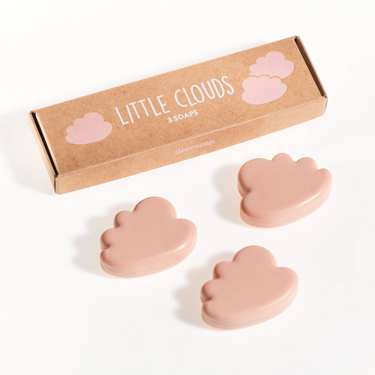 drei kleine rosafarbene Seifen in Wolkenform in geöffneter Verpackung aus Kraftpapier, davor eine geschlossene Verpackung