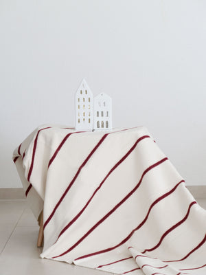 Wollweiße Decke mit roten Streifen, dekoriert mit einem weißen Lichterhaus