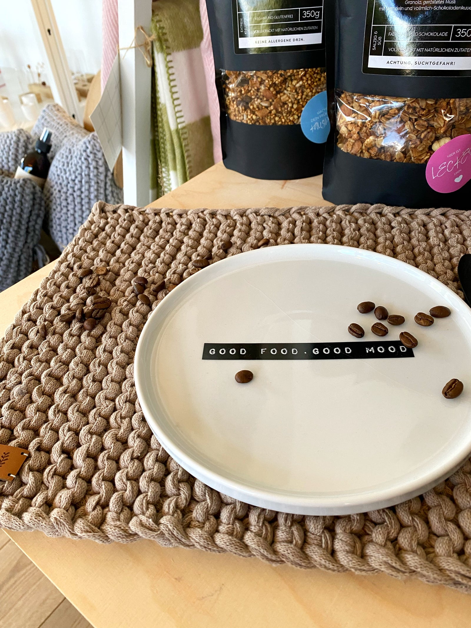 Aufsicht eingedecktes, handgestricktes Platzset in leinen mit weißem Teller und Tasse sowie schwarzem Messer