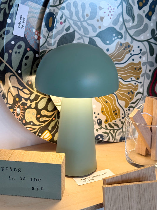 angeschaltete, kleine, kabellose Lampe in Pilzform, grün auf regalbord