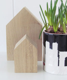 Zwei unterschiedlich große Dekohäuser aus unbehandeltem Eichenholz neben einer schwarz-weißen Tasse gefüllt mit einer grünen Pflanze. Vielseitig einsetzbar als minimalistisches Wohnaccessoire.