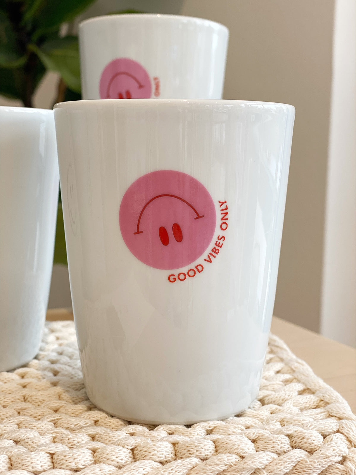 Detailaufmnahme eines eißen Bechers mit einem rosa Smiley und dem Aufdruck "good vibes only"