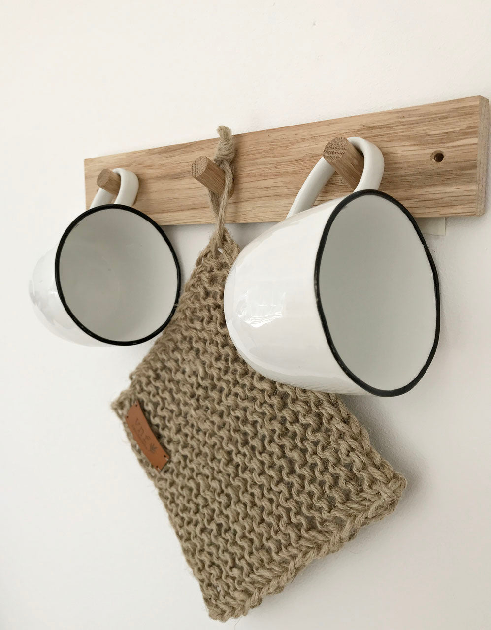 Hakenleiste aus Eiche mit drei Haken, an denen zwei weiße Tassen und einem Untersetzer aus Jute hängen
