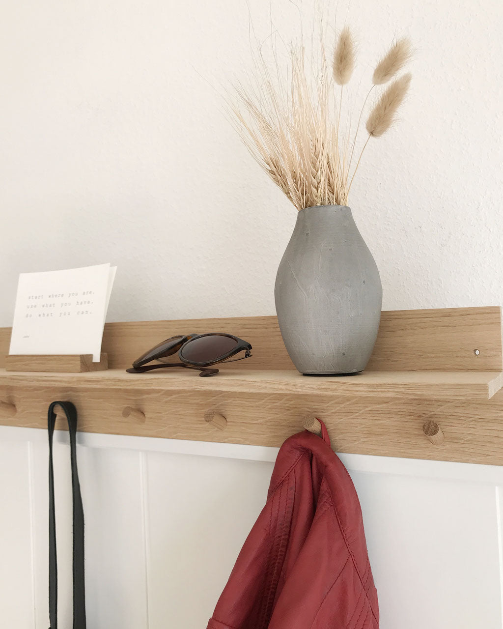 Detailansicht der Hakenleiste XL von Stadtrandstil. Auf dem Bord stehen ein Kartenhalter mit Postkarte, eine graue Vase mit Trockengräsern und eine Sonnenbrille. 