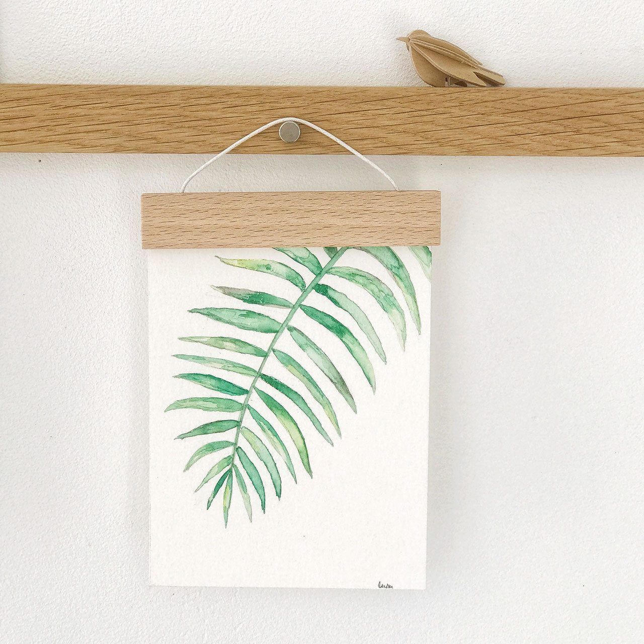 handgemalte Postkarte mit einem grünen Blatt, das an einer kleinen Holzleiste befestigt ist