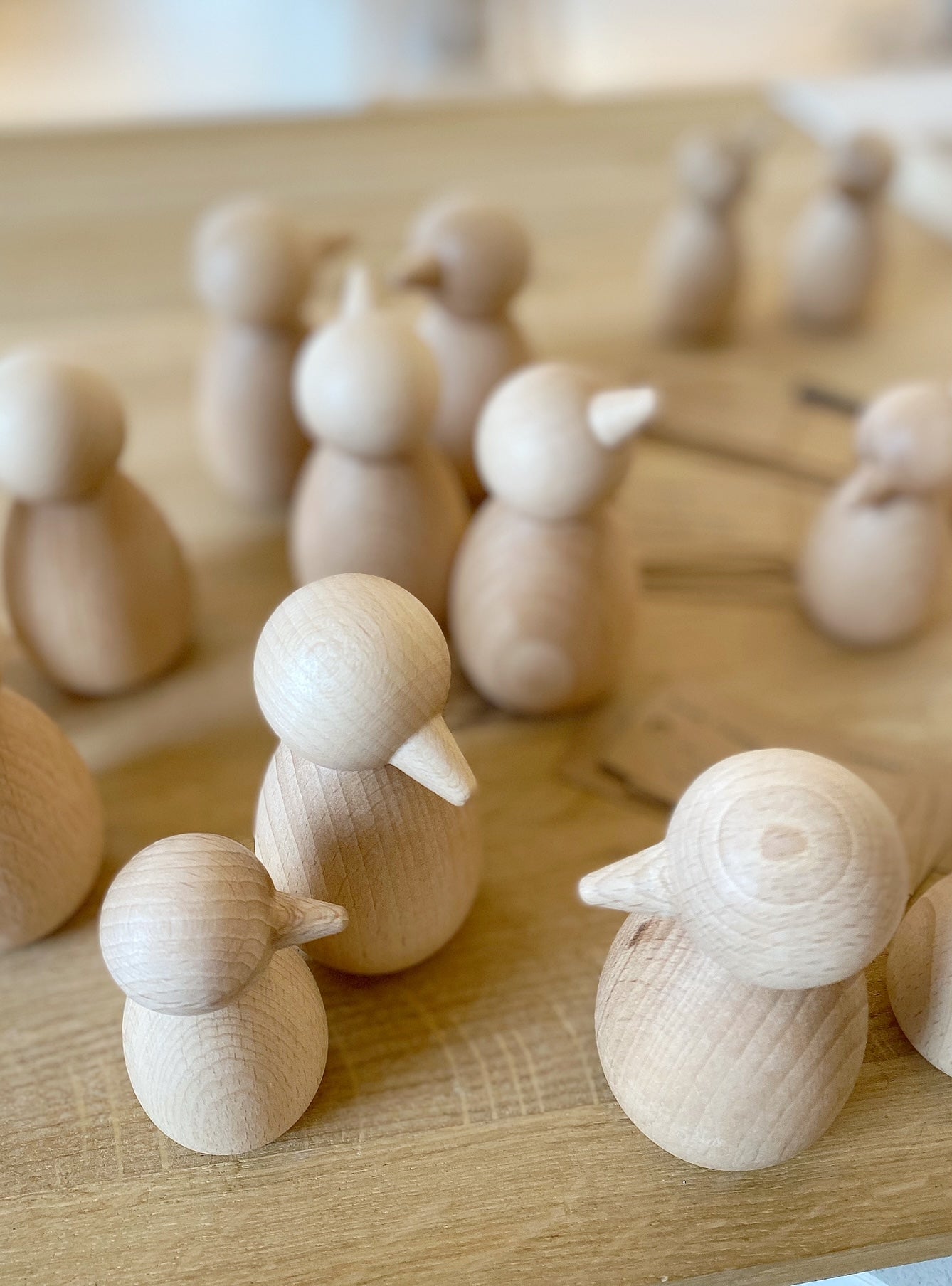 Hübsch arrangiertes Küchenbild: ein grauer, handestrickter Untersetzer, auf dem en kleiner Holzvogel sowie ein weißer Becher mit der AUfschrift "hey you" stehen. kaffeebohnen sind darüber getreut
